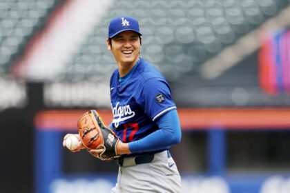 The Japanese pitcher and hitter smiling from the mound while holding a baseball with his glove