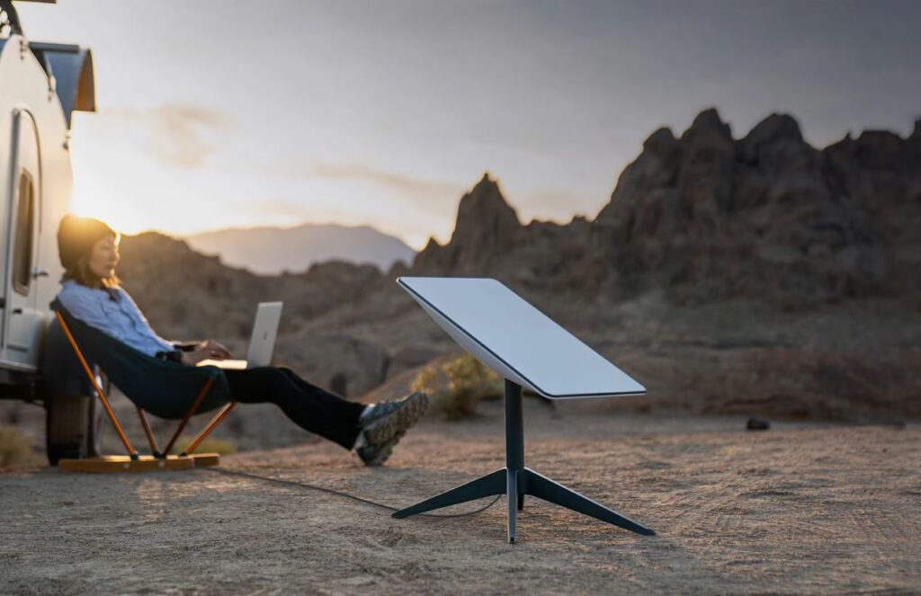 Starlink revamps its plans and promises better connectivity for users A person sitting and using their computer with a Starlink antenna next to them