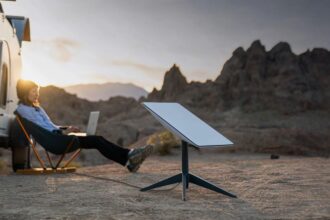 A person sitting and using their computer with a Starlink antenna next to them