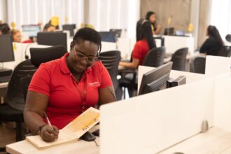 A woman working at a call center in her office while writing in a notebook