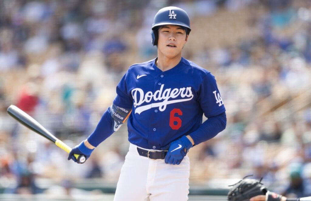 The Asian player from the Los Angeles team holding a bat and watching the ball leave the field after a powerful hit