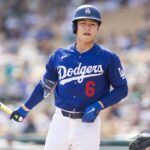 The Asian player from the Los Angeles team holding a bat and watching the ball leave the field after a powerful hit