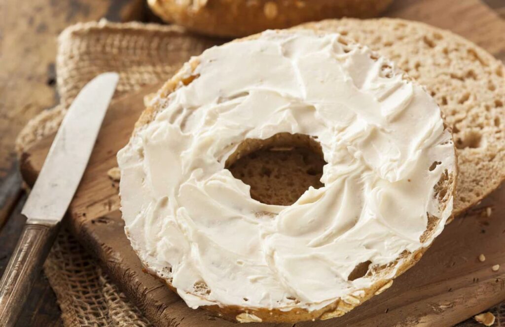 A piece of bread cut in half spread with a generous amount of cream cheese