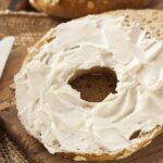 A piece of bread cut in half spread with a generous amount of cream cheese