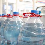 A shelf fully stocked with bottled water in a supermarket