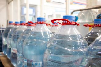 A shelf fully stocked with bottled water in a supermarket