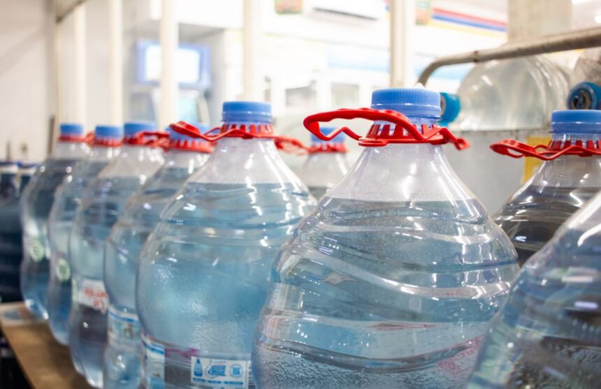 A shelf fully stocked with bottled water in a supermarket