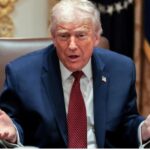 Donald Trump in his presidential office talking to someone with his arms open