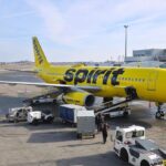 A Spirit Airlines plane being loaded with luggage and passengers at an airport.