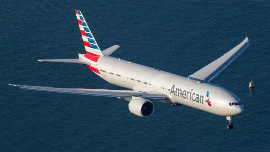 A white American Airlines airplane flying over the sea.