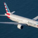 A white American Airlines airplane flying over the sea.
