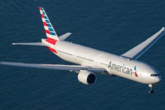 A white American Airlines airplane flying over the sea.