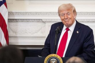 Donald Trump wearing an elegant suit speaking behind a podium.