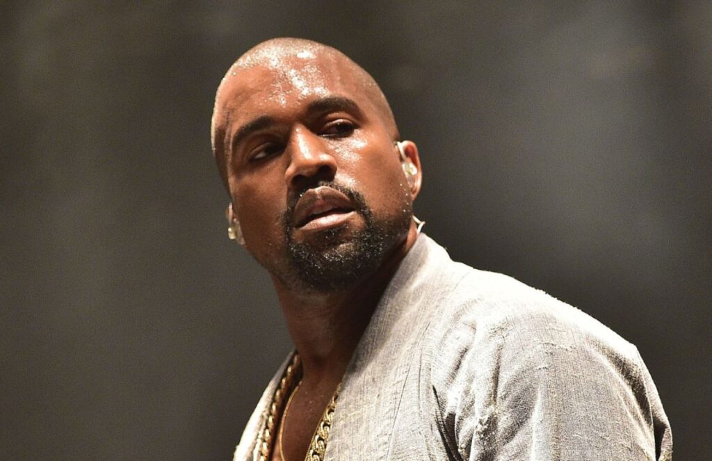 Kanye West in the middle of a concert, covered in sweat while performing his show