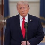 Donald Trump wearing an elegant suit while giving a press conference in front of cameras