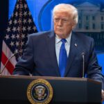 Donald Trump wearing an elegant suit while giving a speech to his supporters.