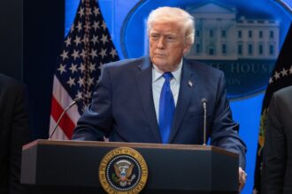 Donald Trump wearing an elegant suit while giving a speech to his supporters.