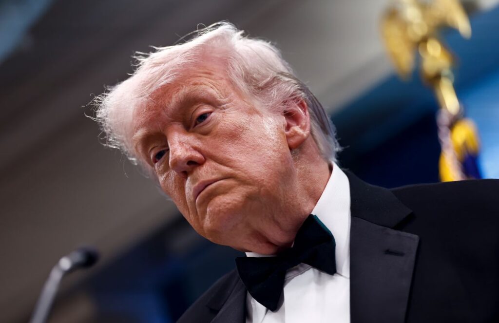 Donald Trump wearing an elegant suit and looking displeased during a meeting.