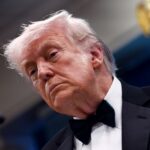 Donald Trump wearing an elegant suit and looking displeased during a meeting.