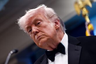 Donald Trump wearing an elegant suit and looking displeased during a meeting.