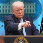 Donald Trump pointing his finger at a person during a conference