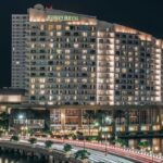 A panoramic nighttime photo of the hotel with all its lights on