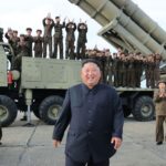 A panoramic image of the leader of North Korea with several soldiers behind him, riding in a bomber vehicle.