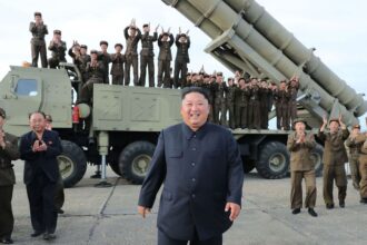 A panoramic image of the leader of North Korea with several soldiers behind him, riding in a bomber vehicle.