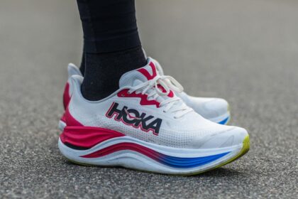 A pair of beautiful white HOKA shoes with red and blue details.