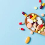 A spoon filled with multiple pills and vitamins, overflowing beyond it.