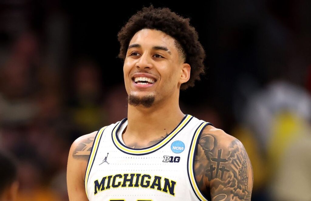 Heroic and injured Yaxel Lendeborg leads Michigan in a historic night The young Michigan player smiling during a game, with his large afro and white uniform