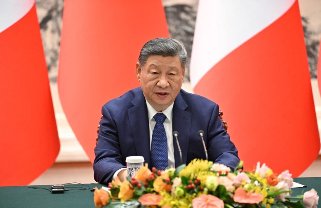 The president and leader of China sitting in front of his followers during a meeting