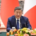 The president and leader of China sitting in front of his followers during a meeting