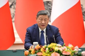 The president and leader of China sitting in front of his followers during a meeting