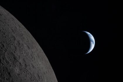 A historic photo of the Moon with a completely black background and planet Earth visible behind it.