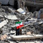 A scene of total destruction with some Iran flags being raised by people