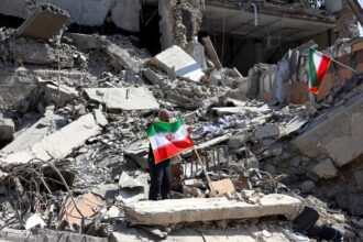A scene of total destruction with some Iran flags being raised by people