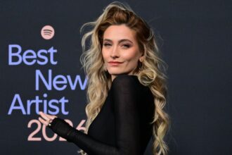 Paris Jackson posing on a red carpet wearing a beautiful black dress.