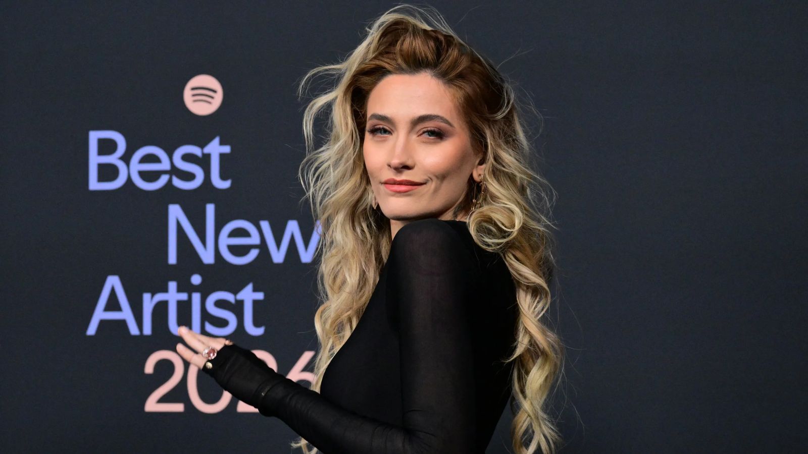 Paris Jackson posing on a red carpet wearing a beautiful black dress.