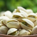 A bowl on a table filled with pistachios ready to eat.