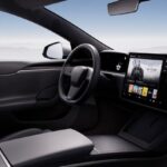 A Tesla car seen from the inside, showing its steering wheel and screen