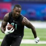 The fast player from the Dallas Cowboys running while holding the ball during a practice.