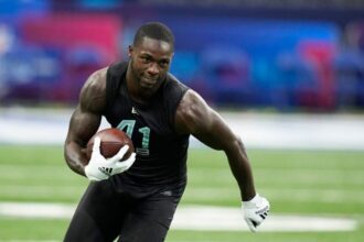 The fast player from the Dallas Cowboys running while holding the ball during a practice.