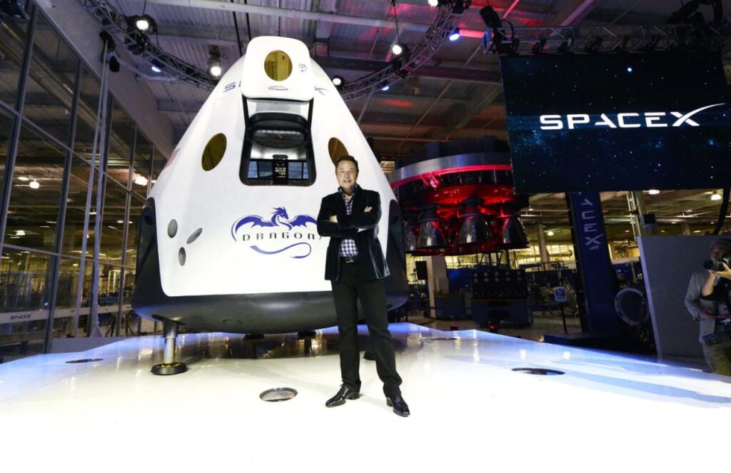SpaceX brings Elon Musk closer to becoming the world’s first trillionaire Elon standing in front of the nose of a SpaceX rocket