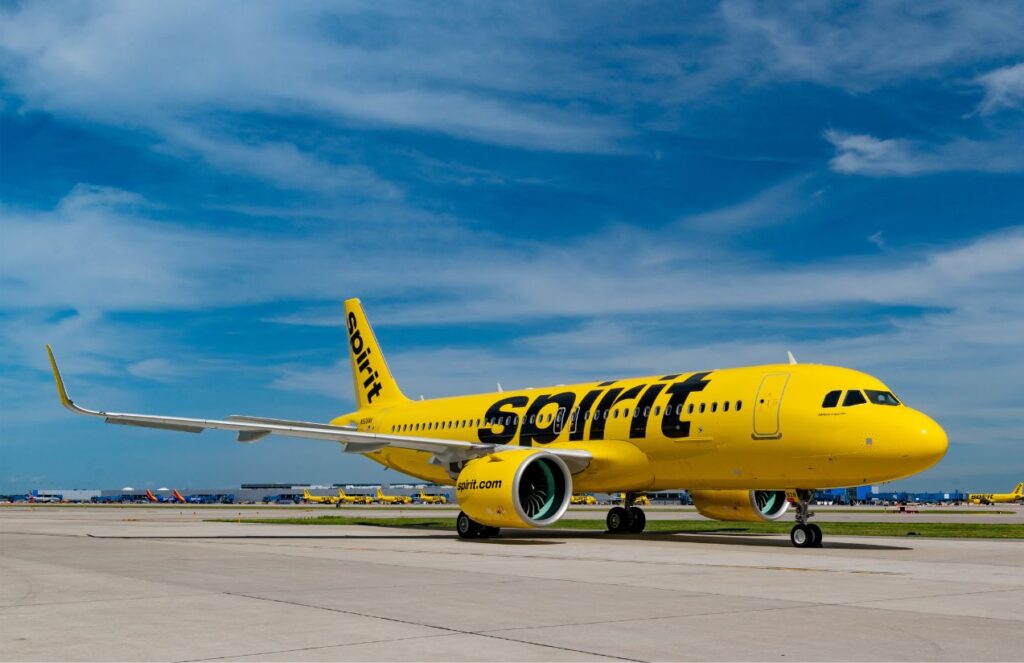 A Spirit Airlines airplane with its distinctive yellow color parked in the middle of an airport.