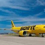 A Spirit Airlines airplane with its distinctive yellow color parked in the middle of an airport.