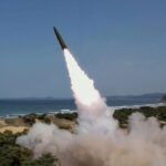 A North Korean tank vehicle launching a missile from the ground toward the sea