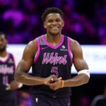 Anthony Edwards holding his hands together while smiling after taking the lead in a game.