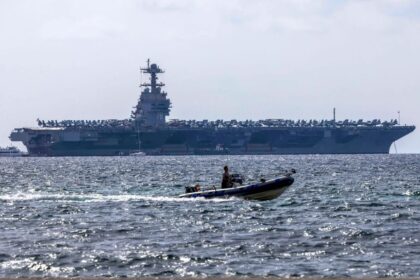 An aircraft carrier on the horizon, awaiting orders at sea.