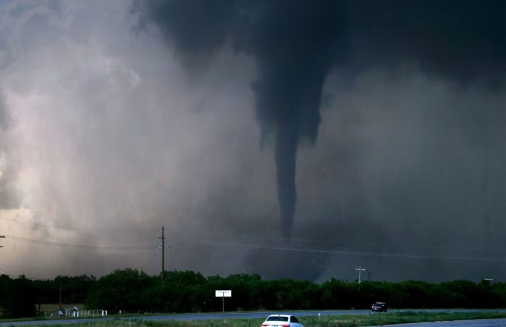 A dangerous tornado crossing a state highway in Oklahoma with several cars nearby.